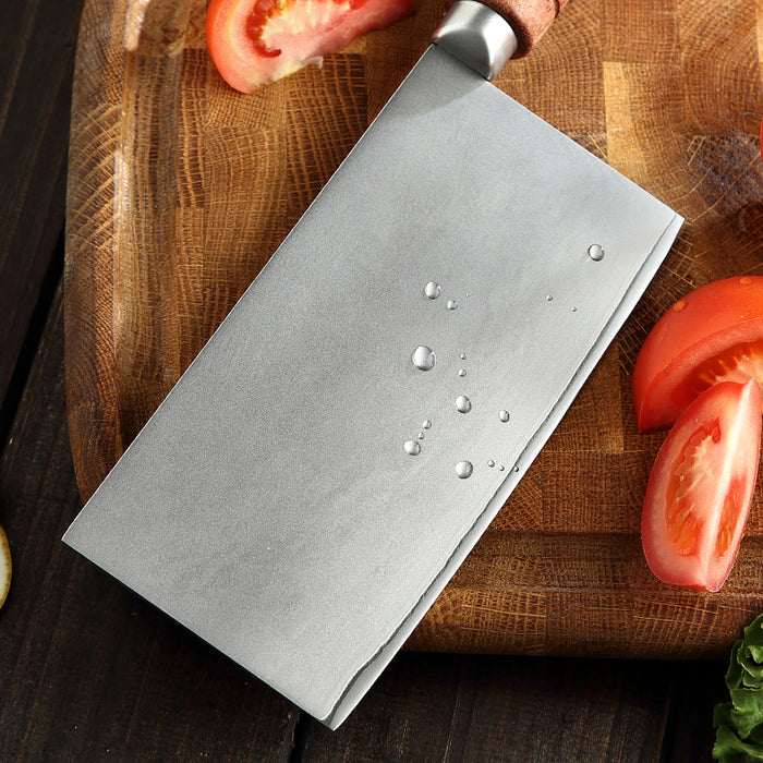 Knife on a wooden cutting board with sliced tomatoes