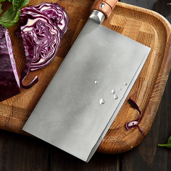 Chef's knife on a wooden cutting board with sliced red cabbage